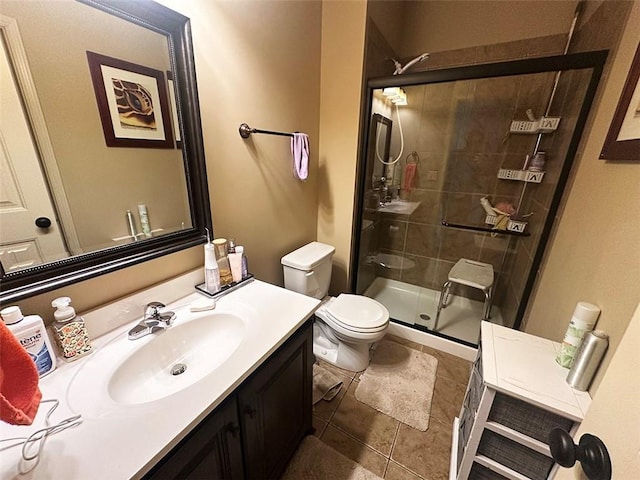 bathroom with vanity, a shower stall, toilet, and tile patterned floors