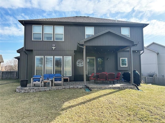 back of property featuring fence, a patio area, and a lawn