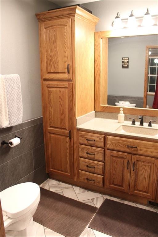 bathroom with vanity, tile walls, and toilet