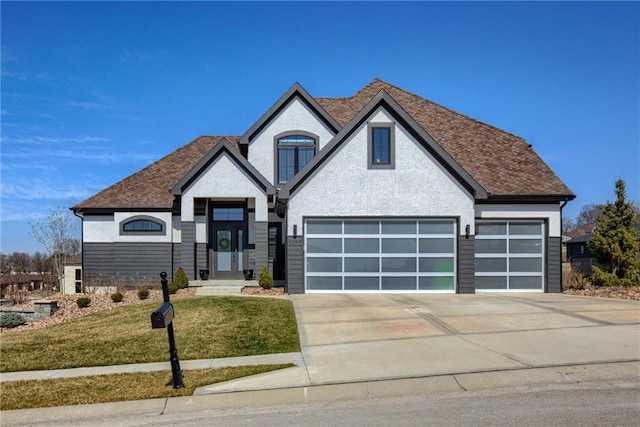 view of front of house featuring an attached garage, a front lawn, roof with shingles, and driveway