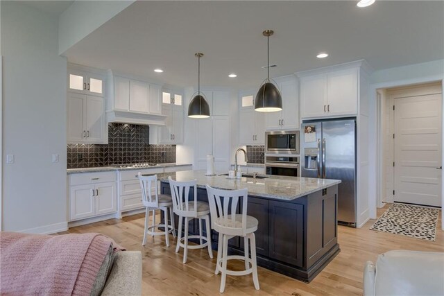 kitchen featuring a sink, stainless steel appliances, tasteful backsplash, and white cabinetry