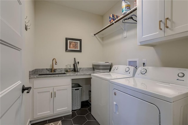 washroom with a sink, cabinet space, dark tile patterned flooring, and washing machine and clothes dryer