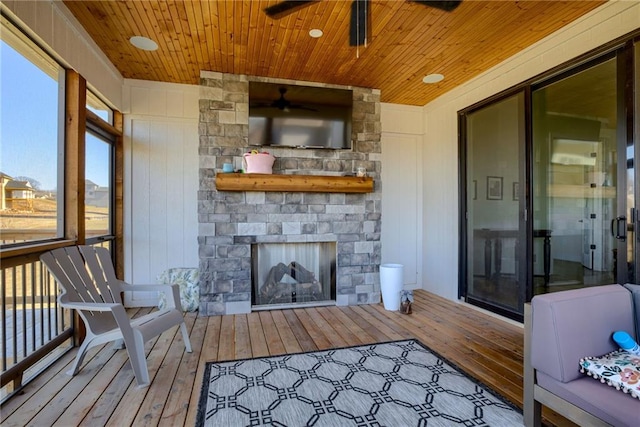 living room featuring wood ceiling, an outdoor stone fireplace, ceiling fan, and hardwood / wood-style floors