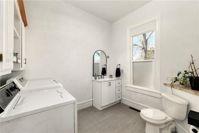 laundry area with visible vents, baseboards, laundry area, independent washer and dryer, and a sink