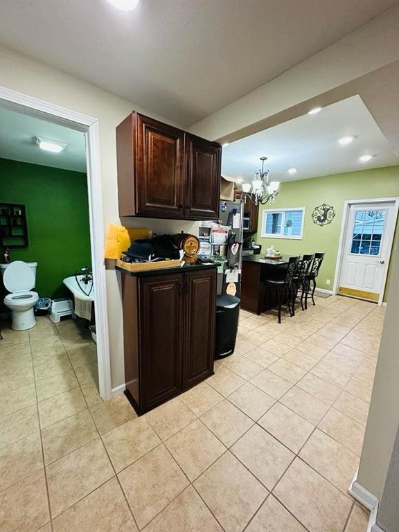 kitchen with dark brown cabinets, recessed lighting, a chandelier, and light tile patterned floors