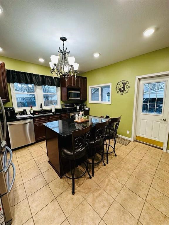 kitchen with dark brown cabinets, a sink, a chandelier, a breakfast bar area, and stainless steel appliances