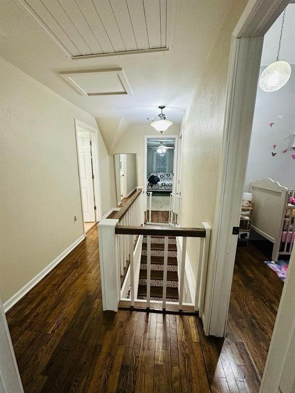 corridor featuring attic access, baseboards, an upstairs landing, and hardwood / wood-style floors