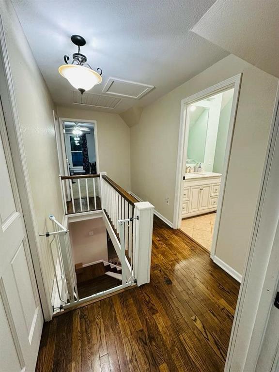 hallway featuring a sink, an upstairs landing, attic access, hardwood / wood-style flooring, and baseboards