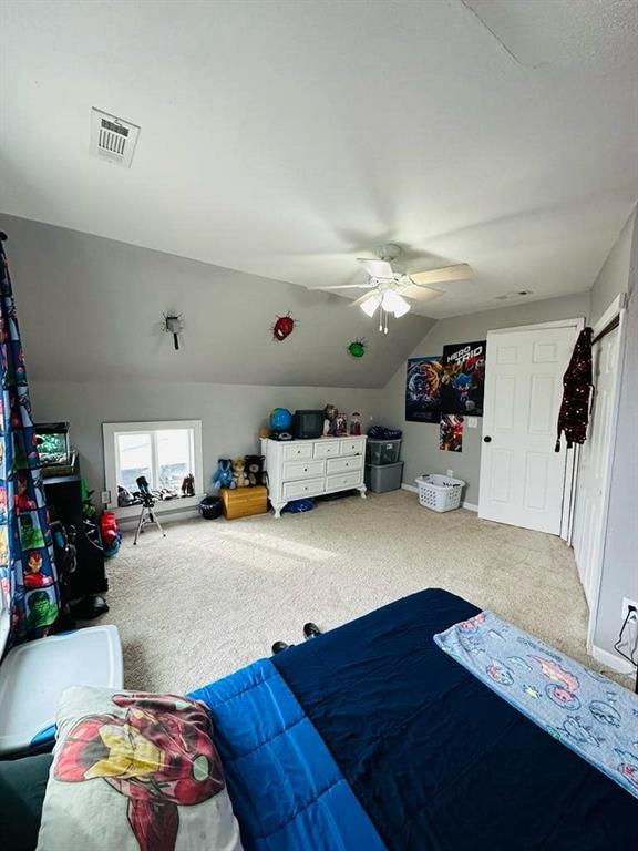bedroom with vaulted ceiling, visible vents, carpet, and ceiling fan