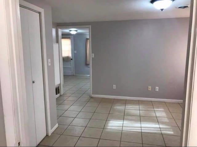 empty room featuring light tile patterned flooring, visible vents, and baseboards