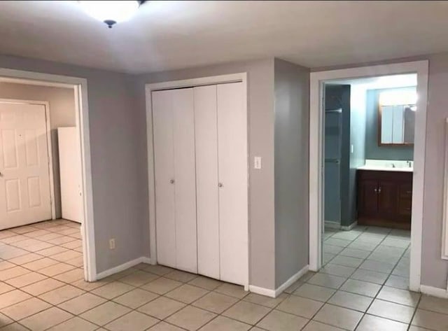unfurnished bedroom with baseboards, light tile patterned flooring, and a closet