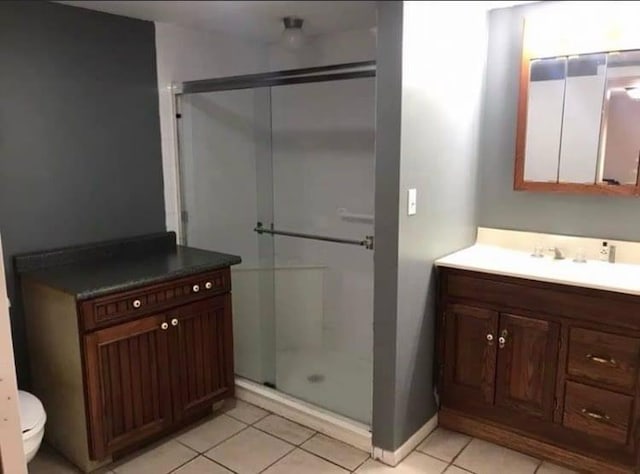full bath featuring a shower stall, toilet, vanity, baseboards, and tile patterned flooring