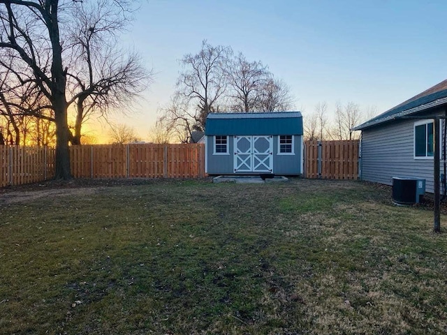 view of yard featuring a fenced backyard, an outdoor structure, central AC unit, and a shed