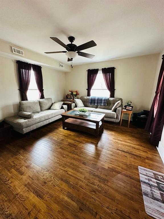 living area featuring wood finished floors, visible vents, and ceiling fan