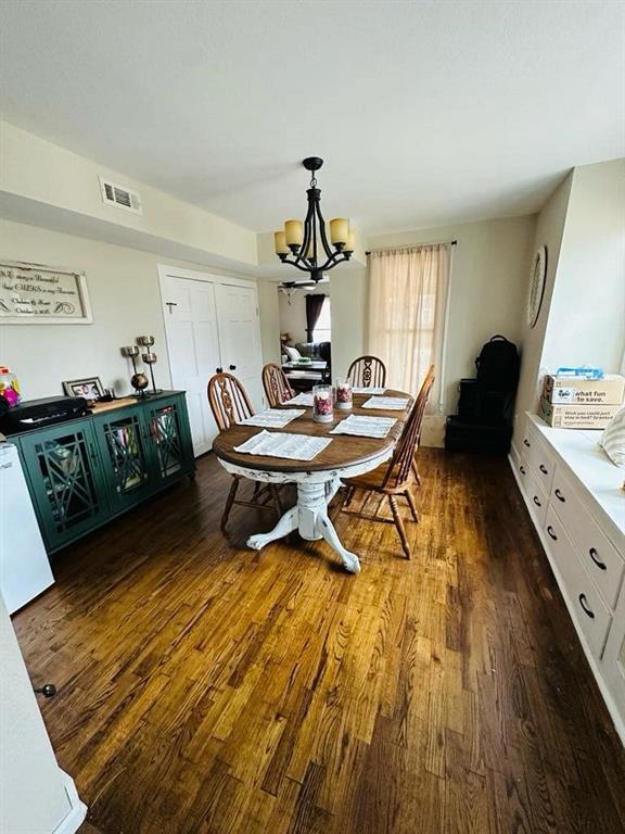 dining area featuring a notable chandelier, visible vents, and dark wood-type flooring
