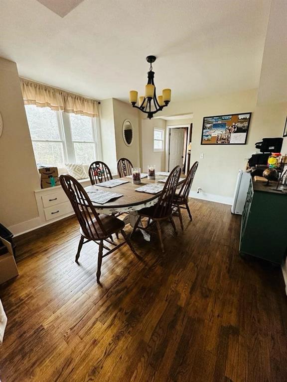 dining room with baseboards, a notable chandelier, and dark wood-type flooring