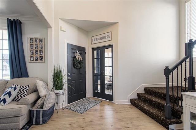 entryway with a wealth of natural light, light wood-type flooring, and stairs