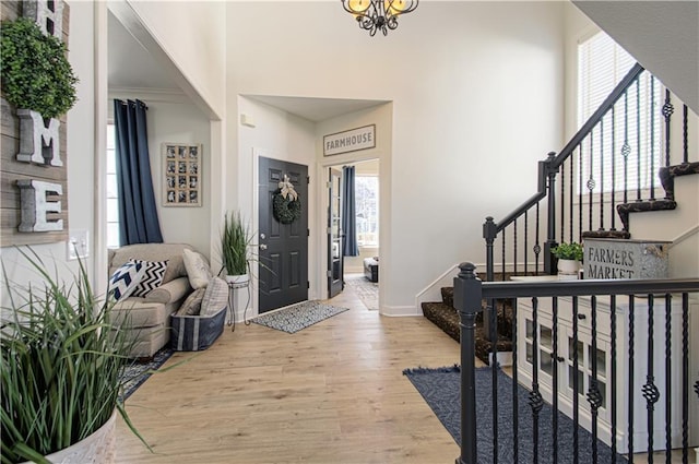 entryway featuring baseboards, a high ceiling, wood finished floors, and stairs