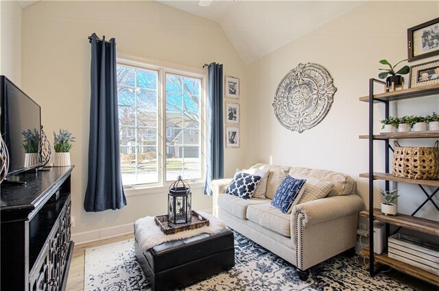 living area with vaulted ceiling, light wood-style flooring, and baseboards