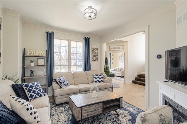 living room featuring a fireplace, crown molding, wood finished floors, and visible vents