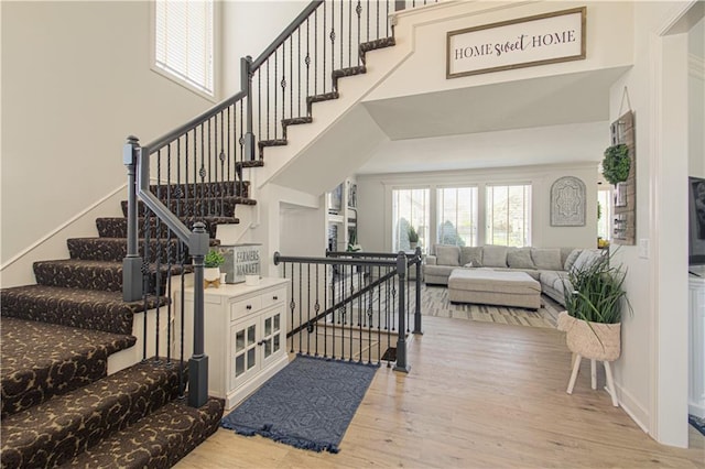 entrance foyer featuring baseboards, a high ceiling, a healthy amount of sunlight, and wood finished floors