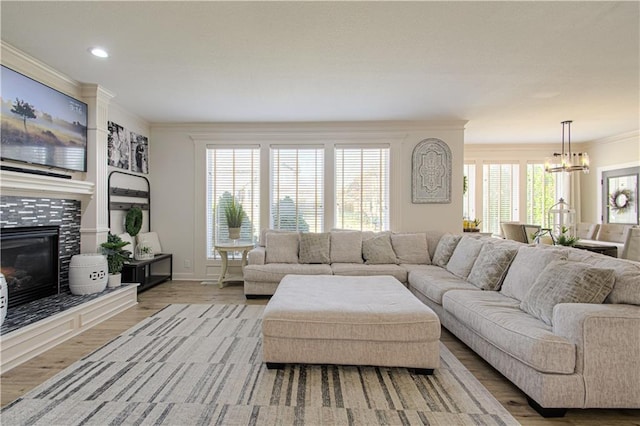 living area with ornamental molding, recessed lighting, a tile fireplace, wood finished floors, and a notable chandelier