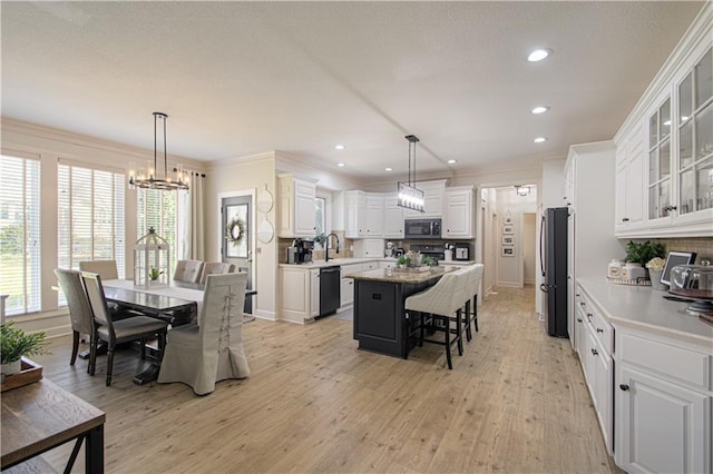 kitchen featuring a breakfast bar, a center island, stainless steel appliances, white cabinets, and a chandelier