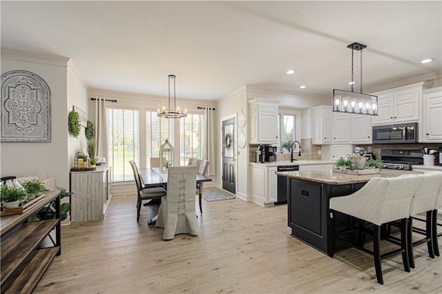 kitchen featuring a notable chandelier, stainless steel microwave, white cabinetry, black gas range oven, and dishwasher