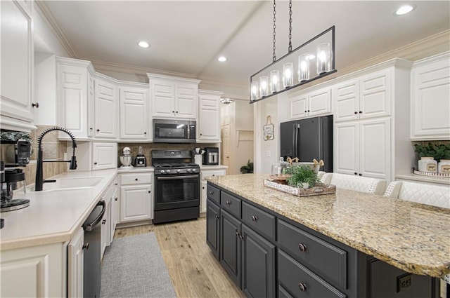 kitchen with white cabinetry, black appliances, and a sink