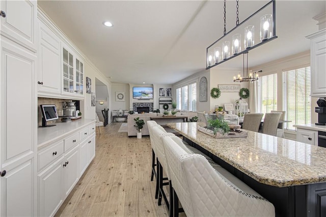 kitchen featuring a kitchen breakfast bar, a notable chandelier, white cabinets, and crown molding