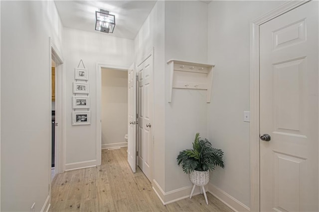 hall featuring light wood-style flooring and baseboards