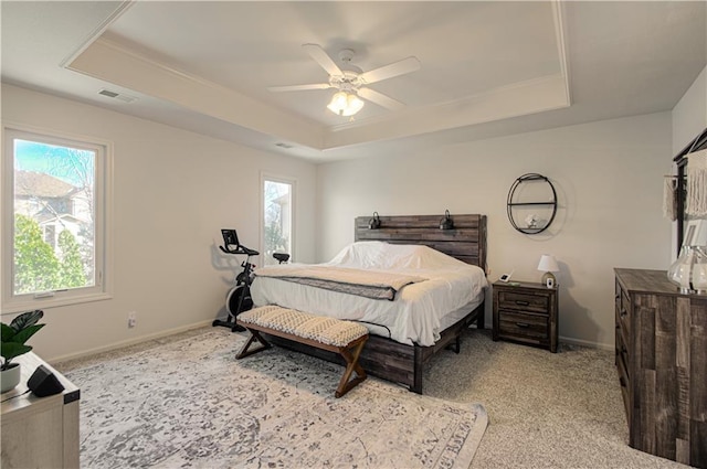 bedroom featuring a tray ceiling, multiple windows, and visible vents