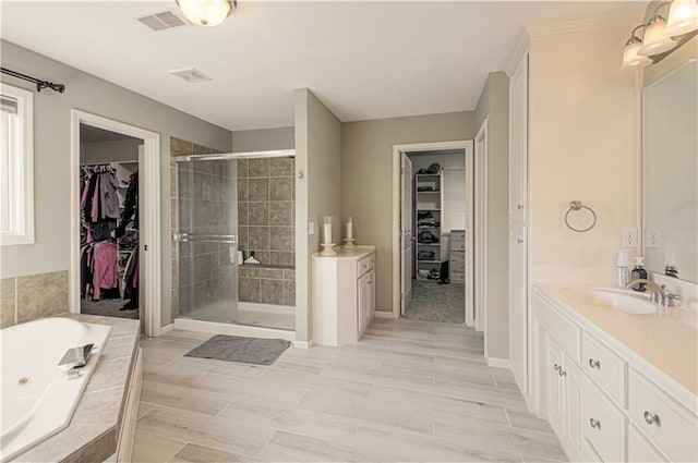 bathroom featuring a spacious closet, visible vents, a whirlpool tub, a stall shower, and vanity