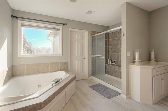 full bath with visible vents, a jetted tub, and a shower stall