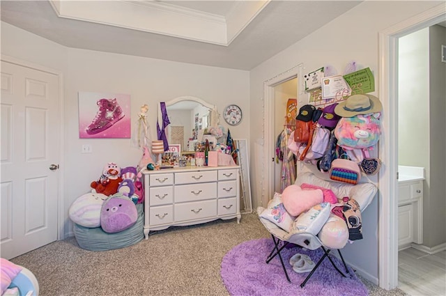 bedroom with a raised ceiling, light colored carpet, and ensuite bath