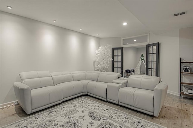 living area with wood finished floors, visible vents, baseboards, recessed lighting, and french doors