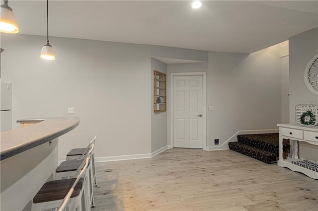 interior space with baseboards, hanging light fixtures, and light wood finished floors