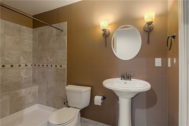 full bathroom with a sink, tiled shower, and toilet