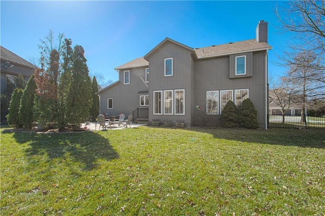 back of property with a patio area, a lawn, a chimney, and fence