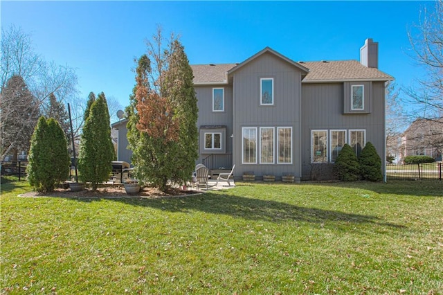 rear view of property with fence, a lawn, a chimney, and a patio area