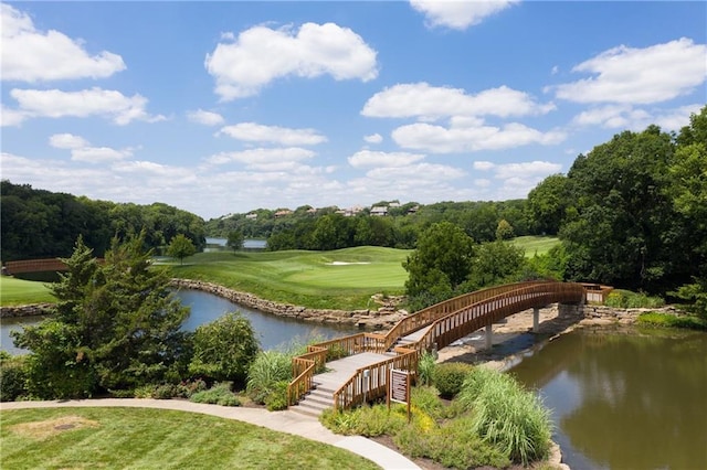 view of community with view of golf course, a yard, and a water view