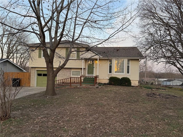 tri-level home with brick siding, a garage, and fence