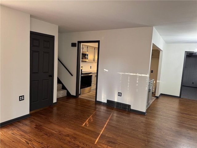 empty room with stairway, baseboards, visible vents, and wood finished floors