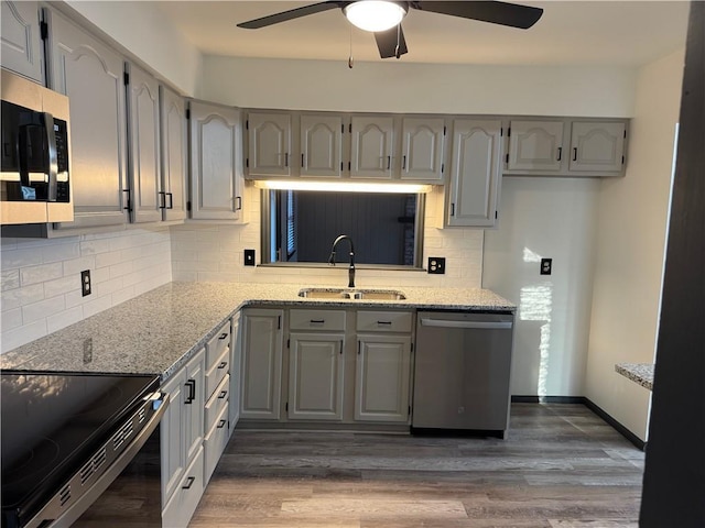 kitchen featuring a sink, stainless steel appliances, gray cabinetry, and wood finished floors