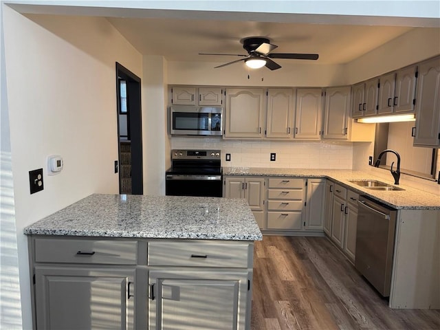 kitchen with dark wood-style flooring, a sink, decorative backsplash, gray cabinetry, and stainless steel appliances