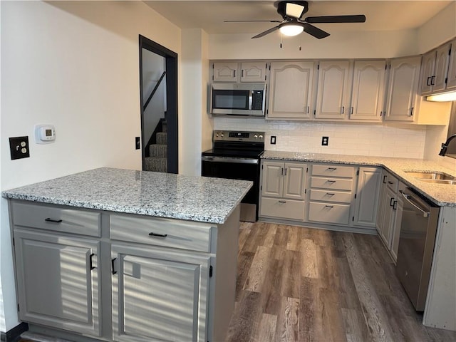 kitchen with a sink, ceiling fan, dark wood-type flooring, gray cabinetry, and appliances with stainless steel finishes