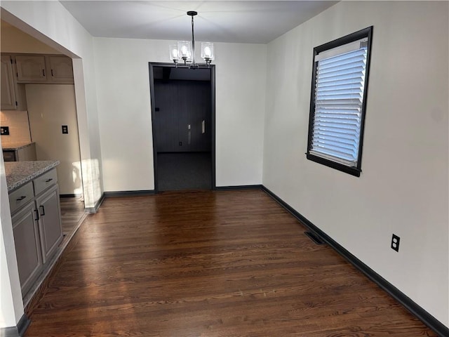 unfurnished dining area with dark wood-type flooring, baseboards, visible vents, and a chandelier