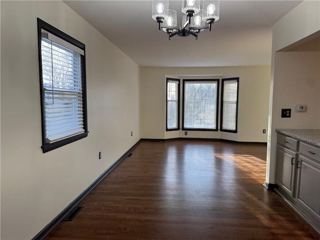 unfurnished dining area with dark wood-style floors, a chandelier, plenty of natural light, and visible vents