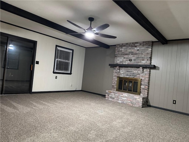 unfurnished living room with a brick fireplace, baseboards, ceiling fan, beamed ceiling, and carpet flooring