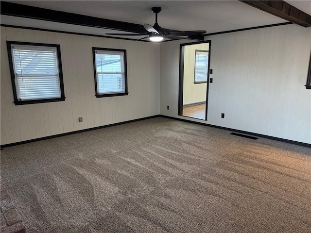 carpeted empty room featuring visible vents, beam ceiling, baseboards, and ceiling fan